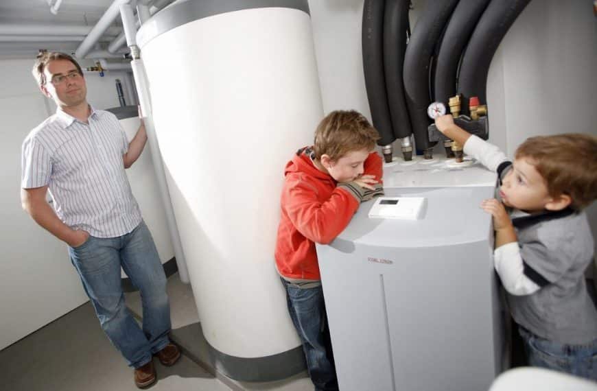 Un homme et deux enfants debout à côté d'un chauffe eau.