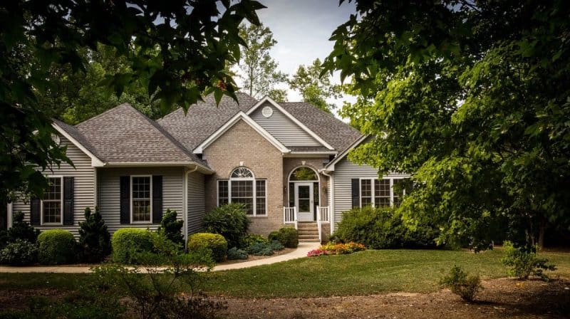 Une maison avec des arbres et des arbustes devant.