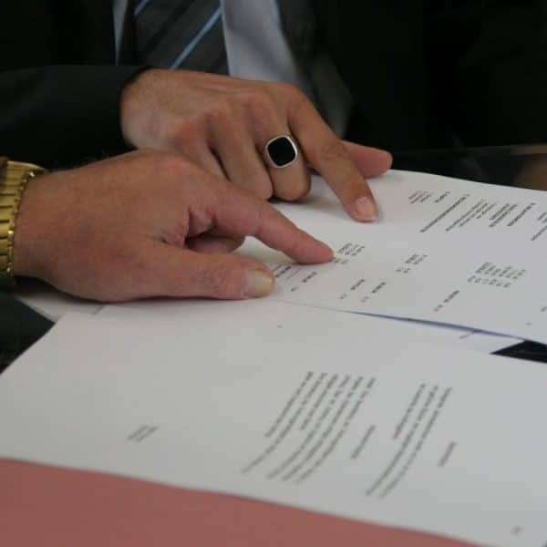 Un homme en costume cravate montre du doigt un morceau de papier.