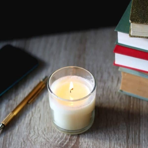 Une bougie est posée au dessus d’une pile de livres et d’un téléphone.
