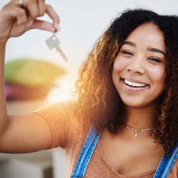 Une jeune femme noire tenant la clé de sa nouvelle maison.