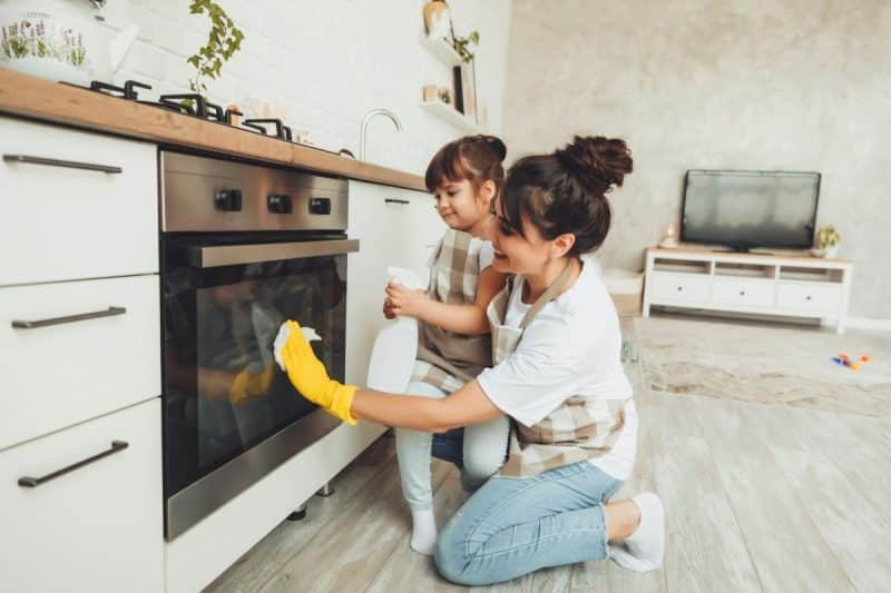 Une mère et son enfant nettoient la cuisine ensemble.
