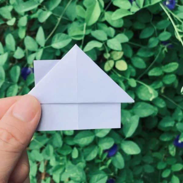 A man holding a house origami. Real estate concept. House for sale or rent