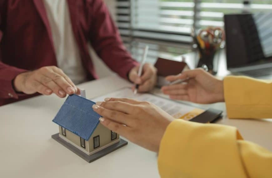 A man signs a contract after agreeing to buy a house with an agent. The agent explains the details o