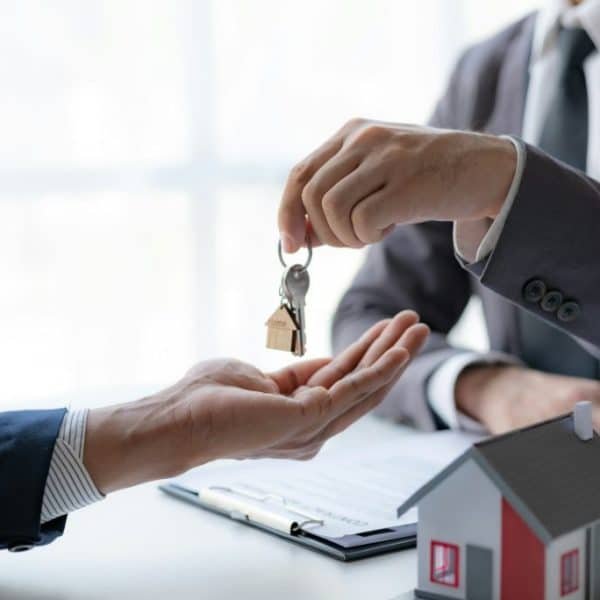 Un homme remet une clé de maison à un autre homme.