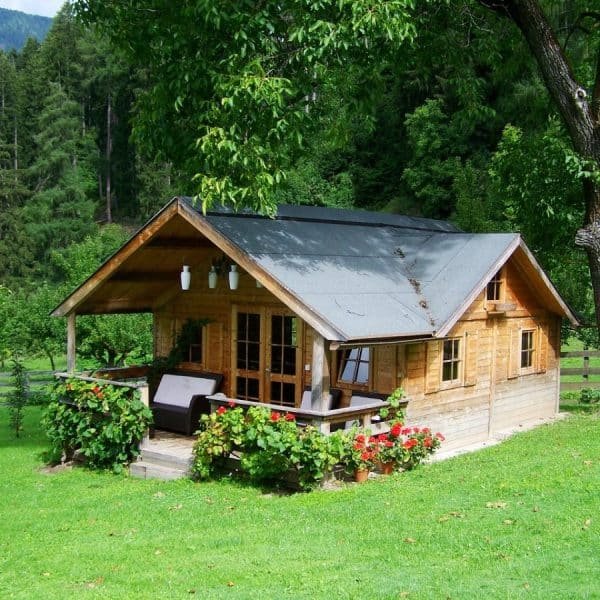 Une petite cabane en bois au milieu d'un champ verdoyant.