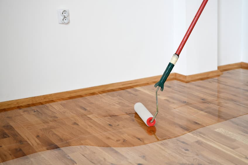 Une personne nettoie un parquet avec un rouleau.