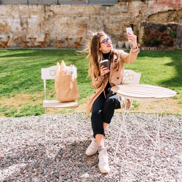Une femme prend un selfie assise sur une chaise.