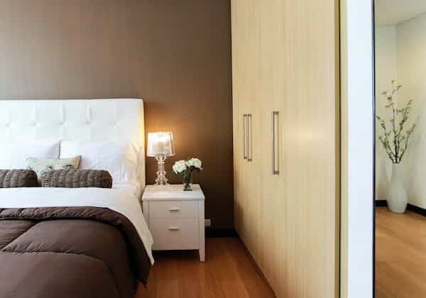 Une chambre avec un lit blanc et une commode marron.