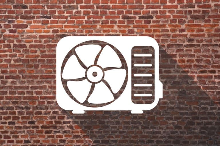 L'icône blanche d'une unité de climatisation avec un ventilateur est affichée sur un fond de mur de briques rouges, projetant une ombre vers la droite.