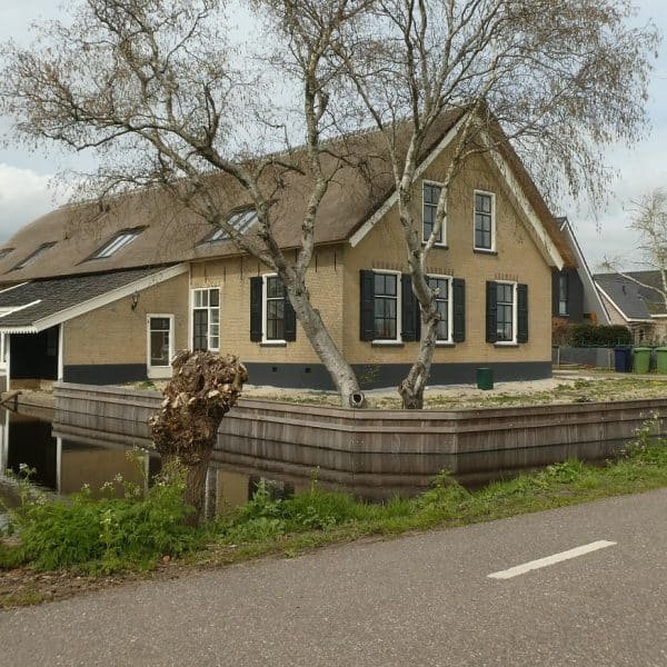 Une maison au toit de chaume au bord d'un canal.