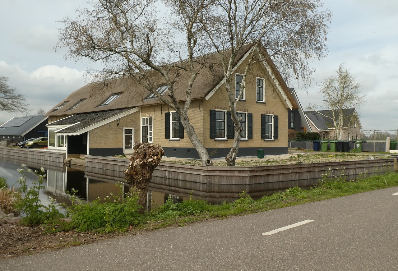 Une maison au toit de chaume au bord d'un canal.
