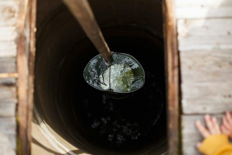 Puits d'eau avec un vieux seau en fer.