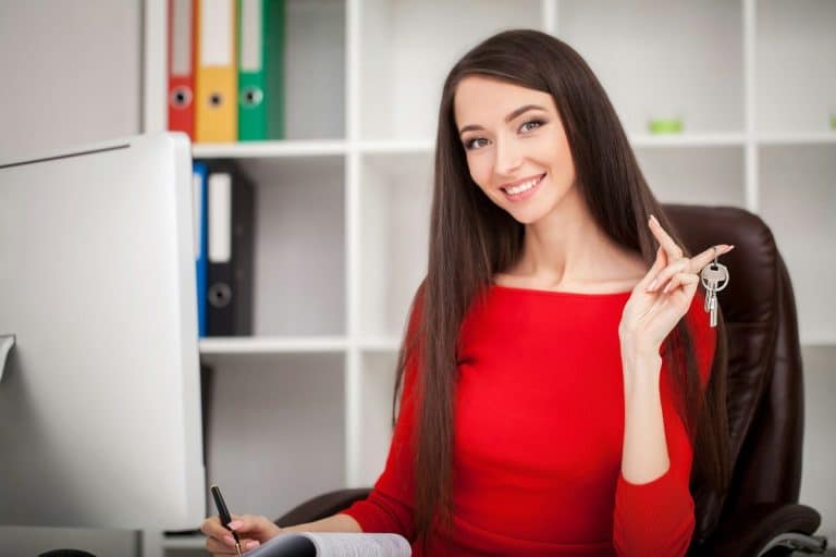 Business women real estate agent holding house and house key selling or renting property for money