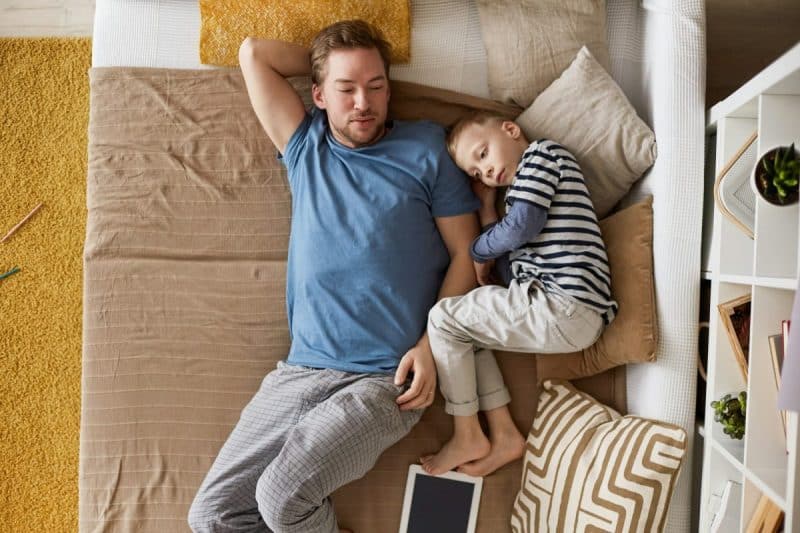 Calm father and son lying on sofa bed