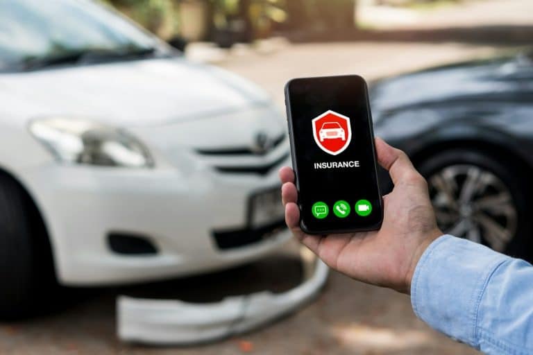 Concept d'assurance automobile : un homme utilise son téléphone pour appeler un agent d'assurance après un accident de voiture.