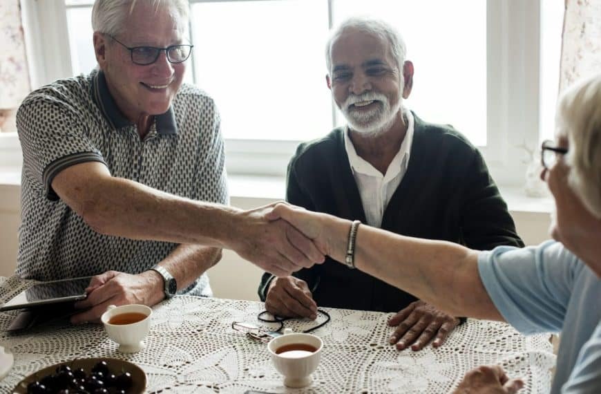 Deux personnes âgées se serrant la main à une table.