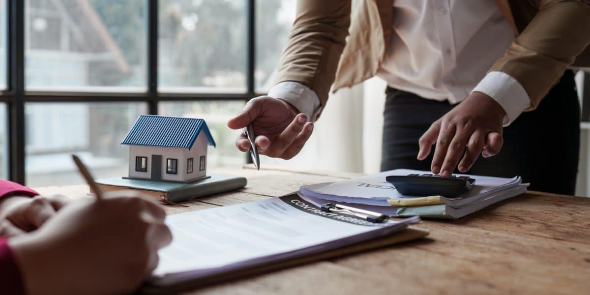 Gros plan Des hommes d'affaires ou un agent immobilier expliquent au client la signature d'un contrat de vente de maison.
