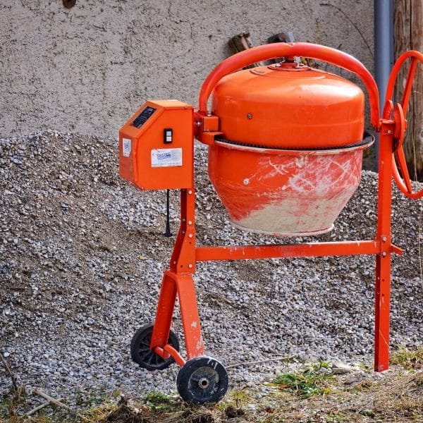 Une bétonnière orange posée sur un tas de terre.