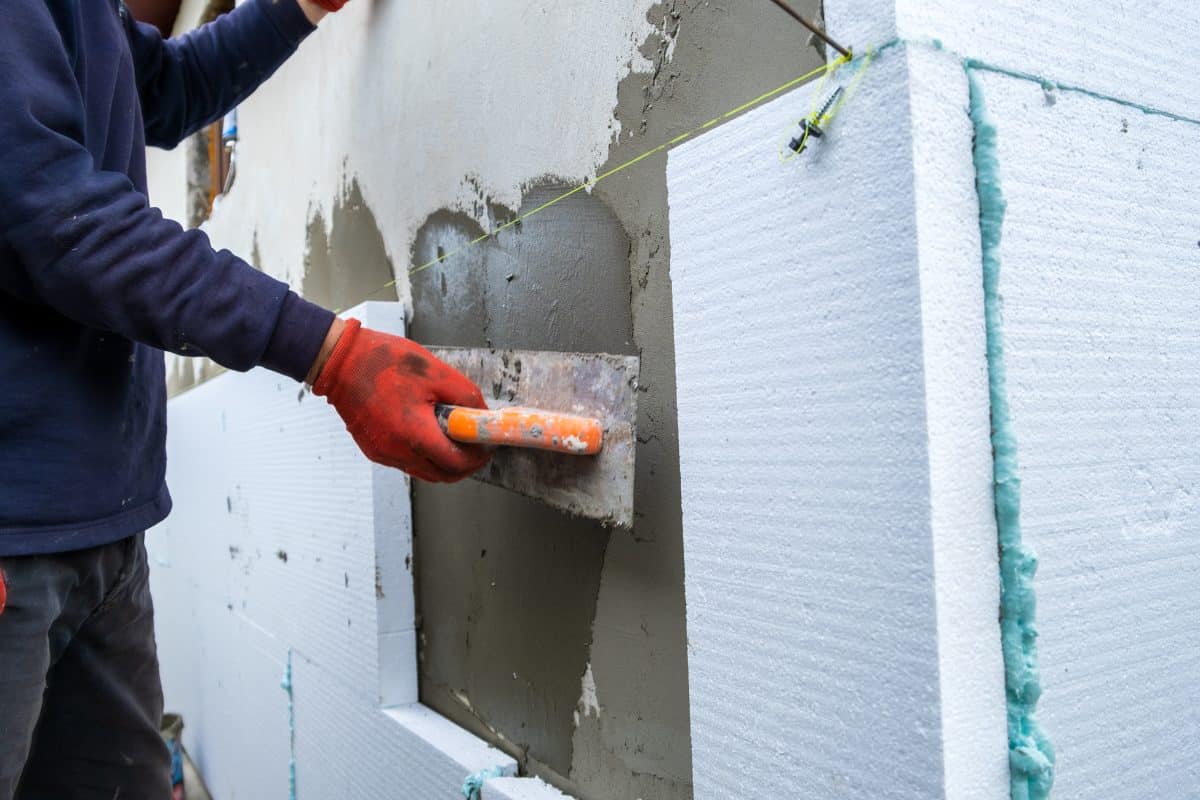 Un homme met du ciment sur un mur.