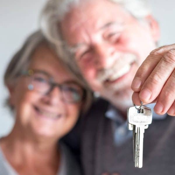 couple of two seniors after buy a new house or car and go to live together - man holding a key