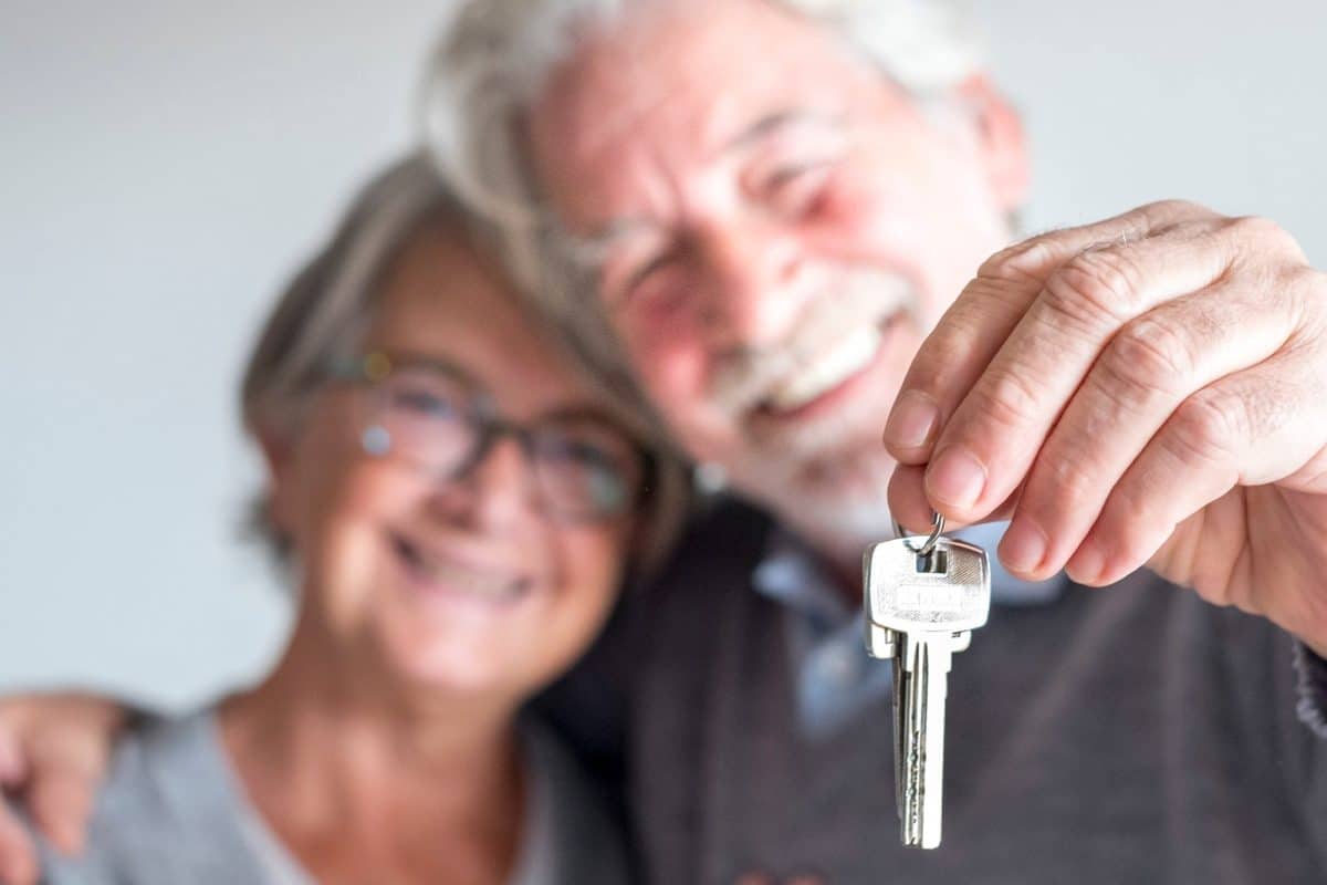 couple of two seniors after buy a new house or car and go to live together - man holding a key