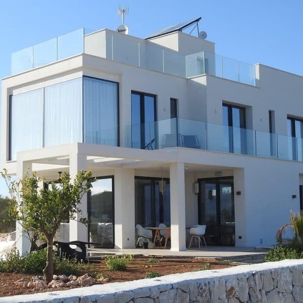 Une maison blanche moderne avec un balcon en verre.