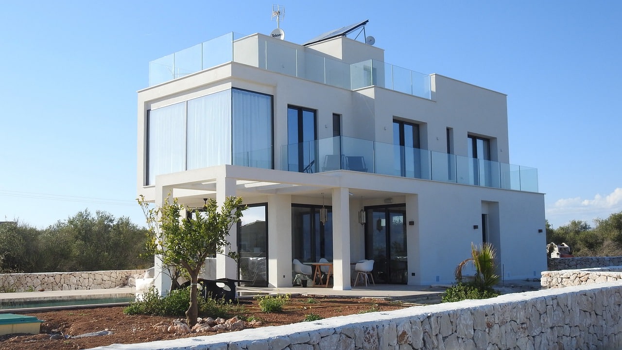 Une maison blanche moderne avec un balcon en verre.