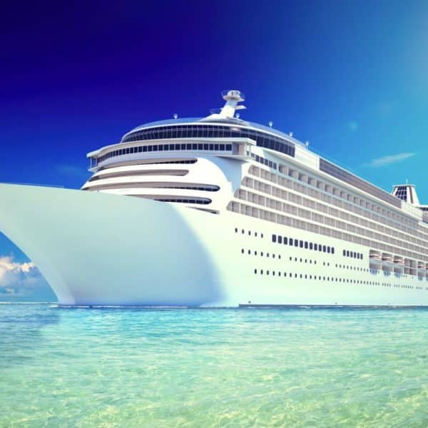 Un grand bateau de croisière blanc naviguant sur une eau bleu clair sous un ciel ensoleillé.