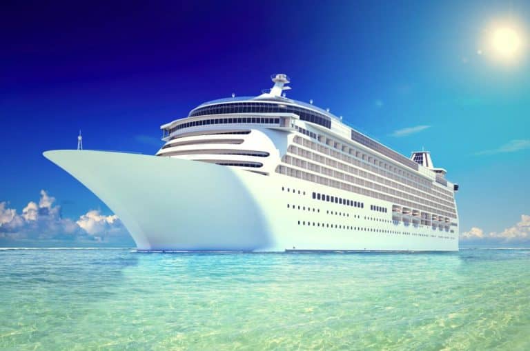 Un grand bateau de croisière blanc naviguant sur une eau bleu clair sous un ciel ensoleillé.