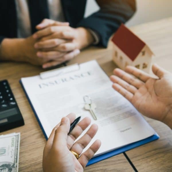 Customers buying houses are negotiating about the cost of home insurance with agents.