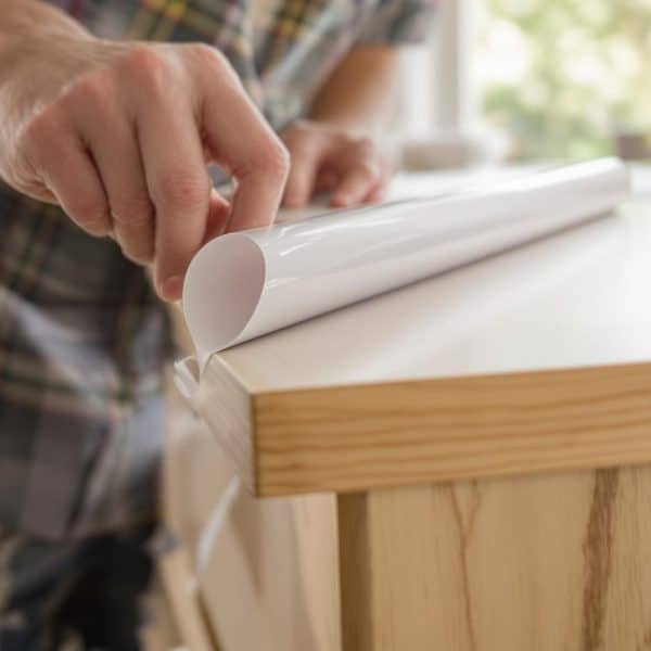 Personne appliquant un revêtement adhésif sur une surface