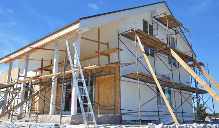 Une maison à deux étages en construction avec des échafaudages et des échelles installés tout autour.