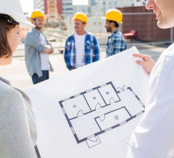 Groupe d'ouvriers de la construction portant des casques de sécurité discutant d'un plan de construction sur un chantier de construction.