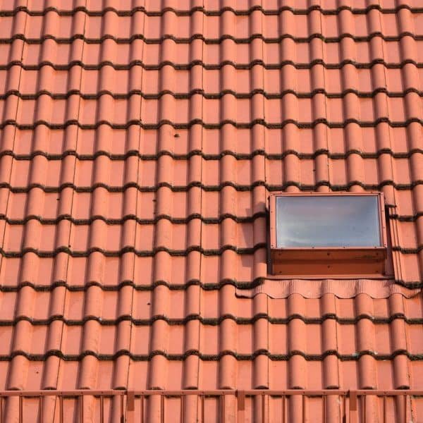 Un toit de tuiles rouges avec une seule petite lucarne près du coin supérieur droit.