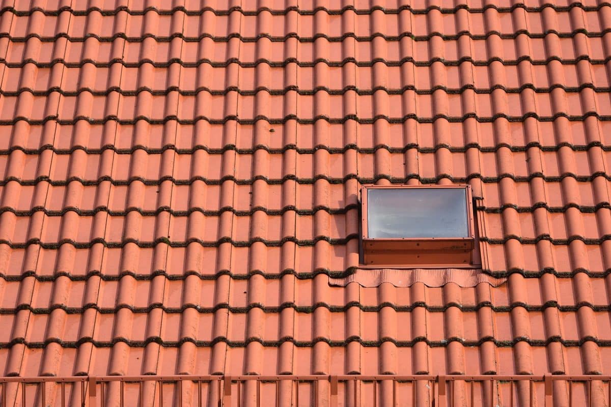 Un toit de tuiles rouges avec une seule petite lucarne près du coin supérieur droit.