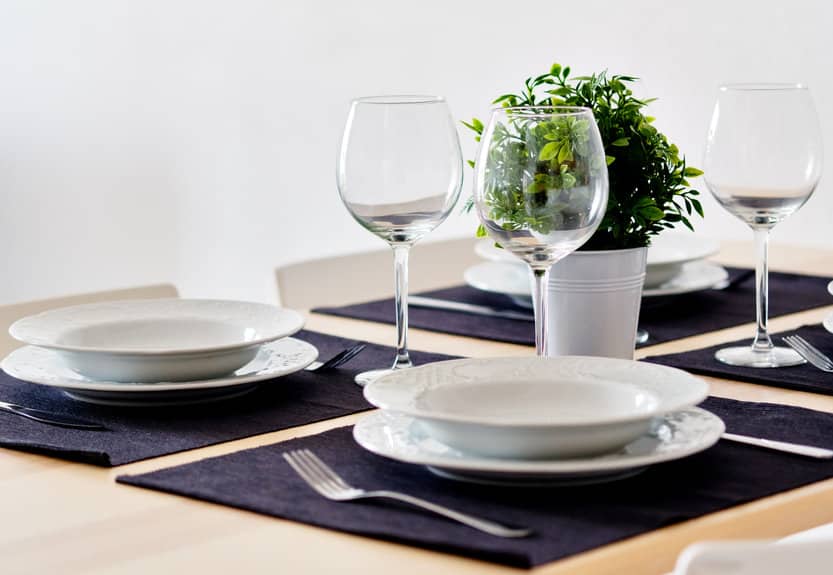 Une table dressée avec des assiettes, des verres et une plante en pot.