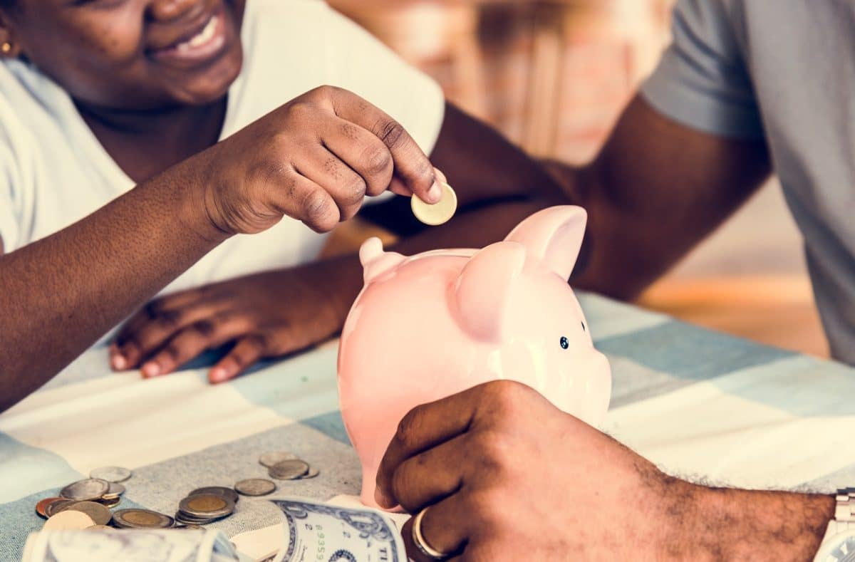 Dad and daughter saving money to piggy bank
