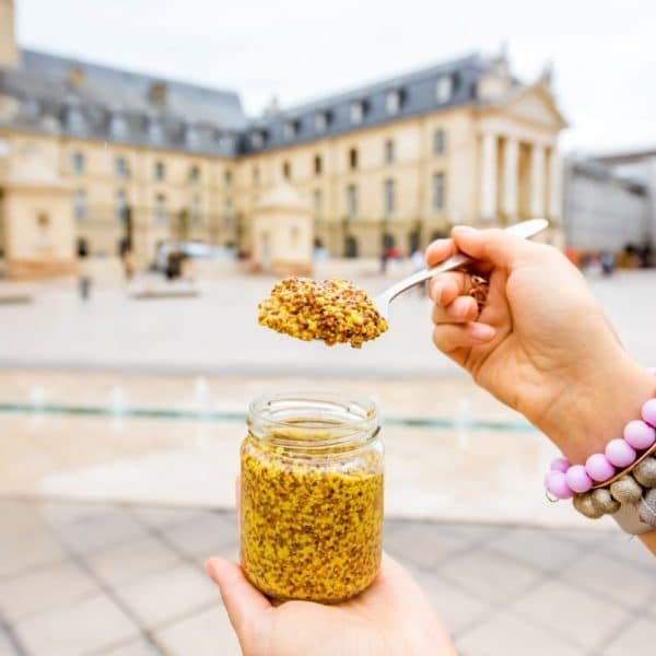 Une personne tient un pot de moutarde sur la place principale de Dijon