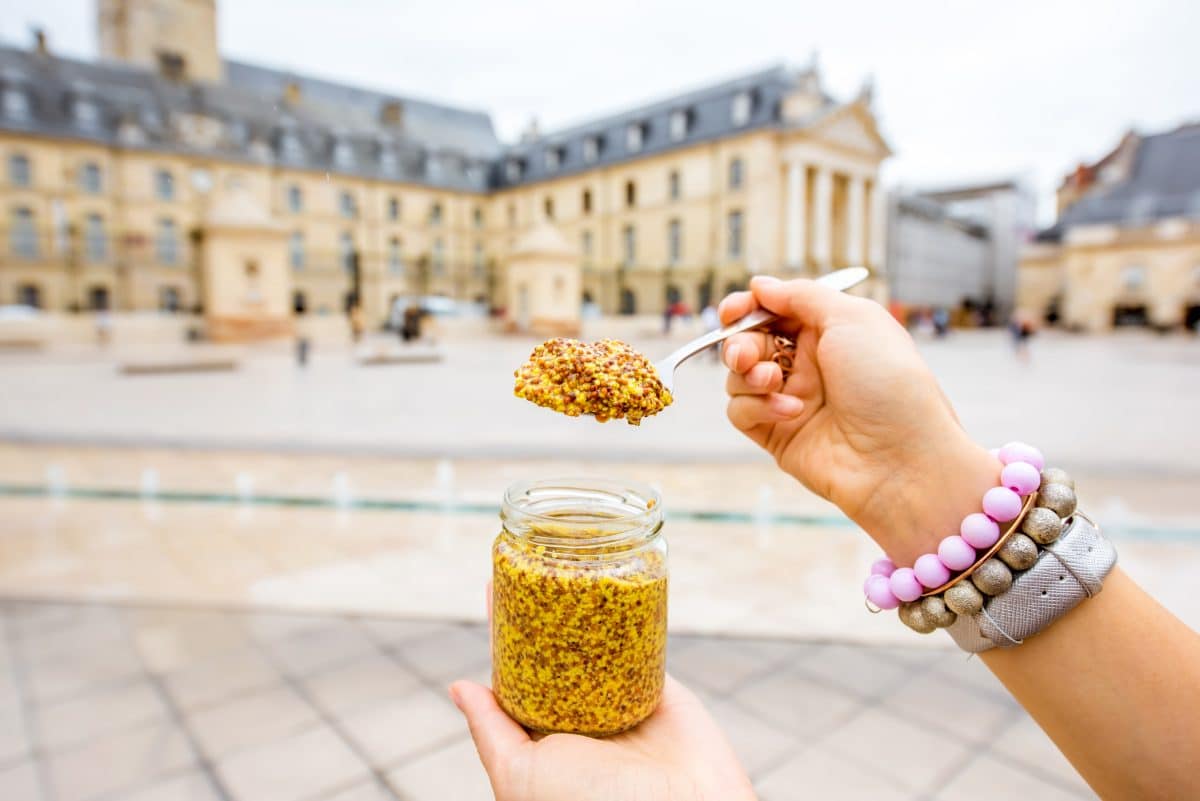 Une personne tient un pot de moutarde sur la place principale de Dijon