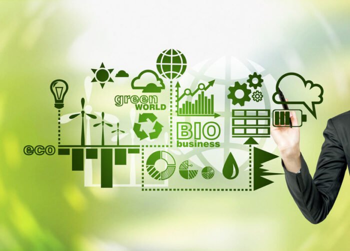 Une personne en costume dessine des icônes d'entreprises écologiques et durables, notamment des éoliennes, des graphiques et des symboles d'énergie verte, sur un écran transparent sur fond de nature verte.