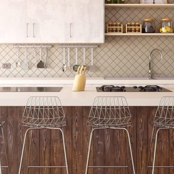 Cuisine moderne comprenant un grand îlot avec quatre tabourets de bar en fil de fer, des armoires lumineuses, une cuisinière à gaz intégrée et des étagères ouvertes présentant divers articles de cuisine.