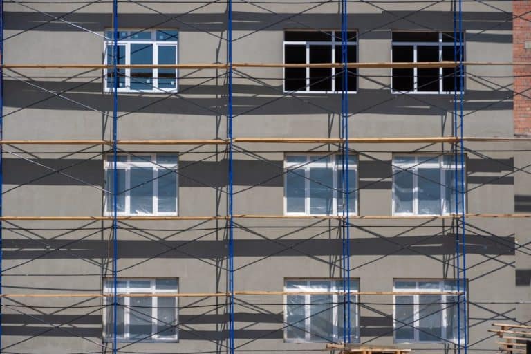 Échafaudage devant une façade d'immeuble avec plusieurs fenêtres.
