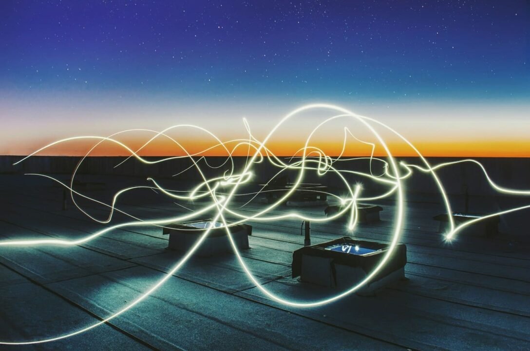 Traînées de « light painting » réalisées en exposition longue sur un toit au coucher du soleil.