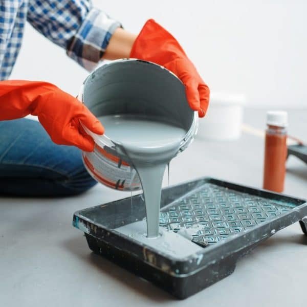 Une femme verse de la peinture dans un seau.