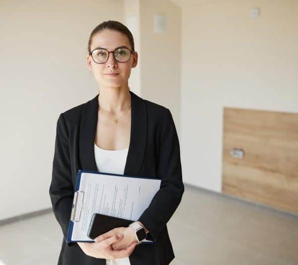 Une femme d'affaires tenant un dossier dans une pièce vide.