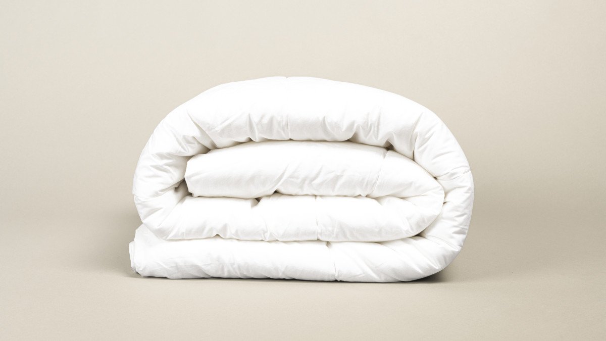 Gros plan sur une couette pliée sur un fond beige