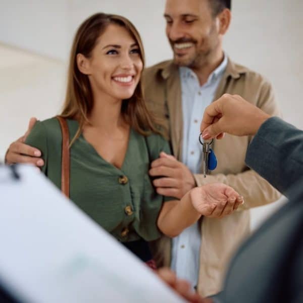 Happy couple receiving keys of their new home from real estate agent.