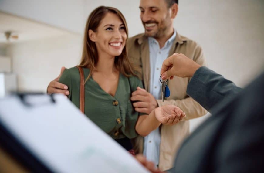 Happy couple receiving keys of their new home from real estate agent.