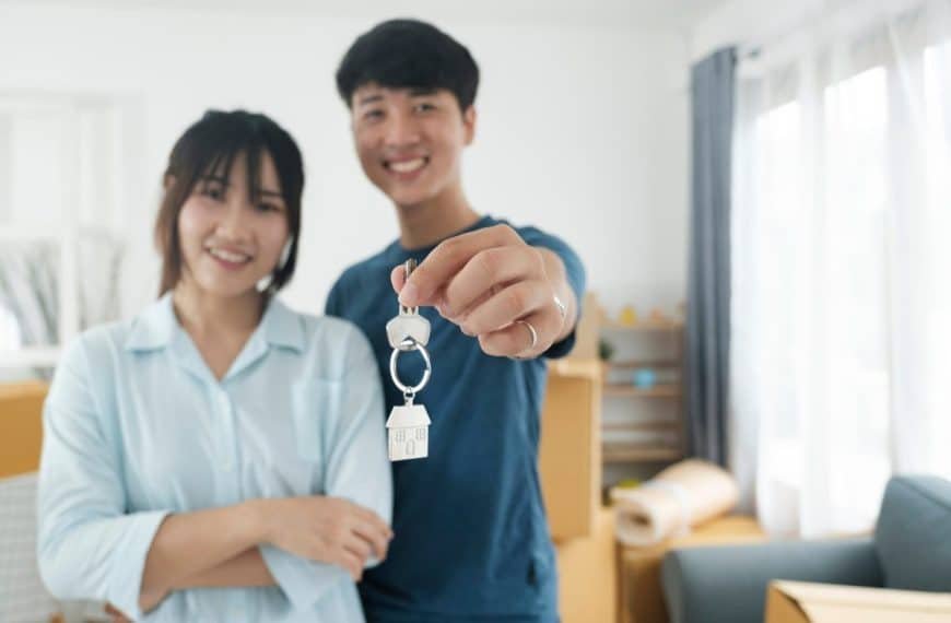 Happy young couple buying a new house receiving the keys.
